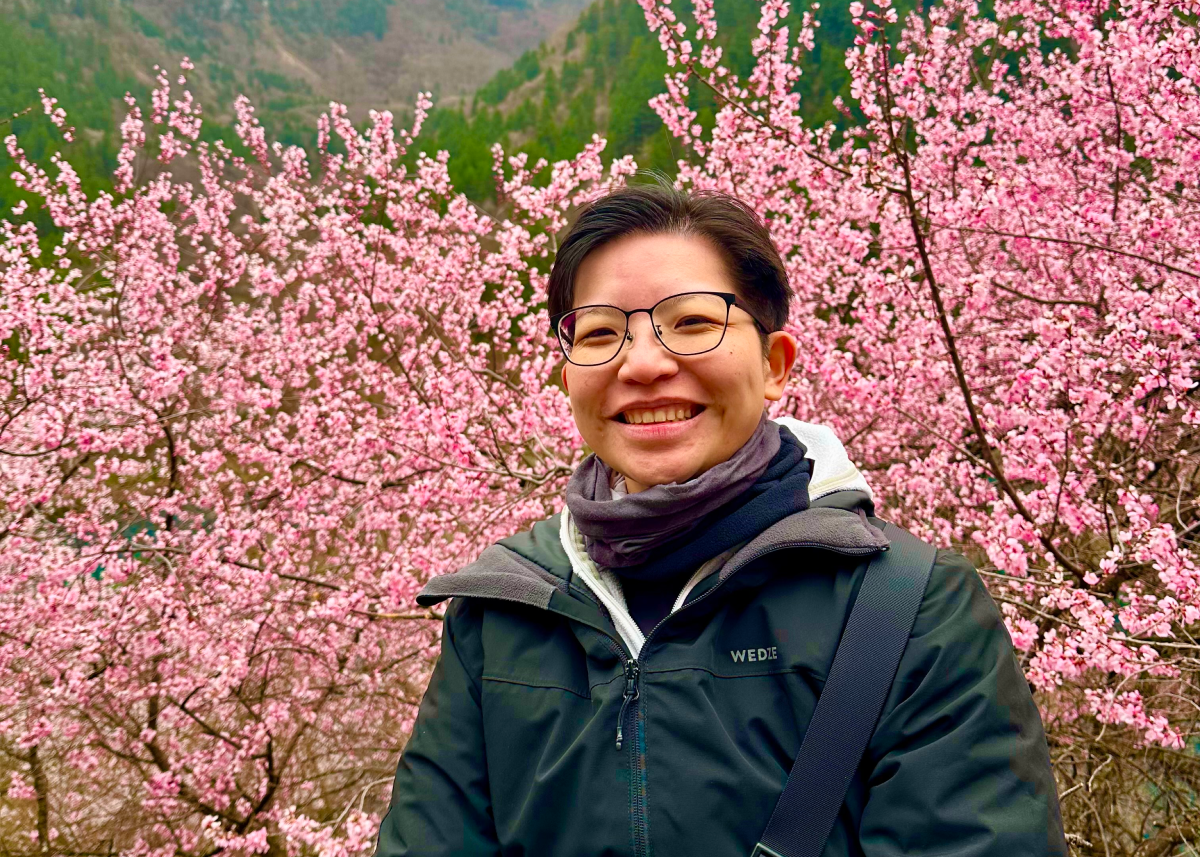 Image of Jalyn, smiling in front of a plant and a window